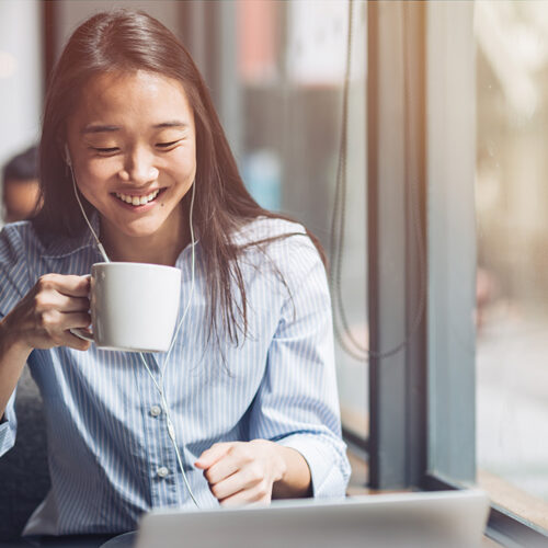 Girl on laptop drinking a cup of coffee